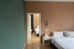 Una camera d'hotel moderna con un letto grande, un comodino e una porta che dà su un'altra stanza.