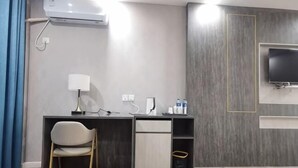 A modern hotel room with a desk, chair, TV, and built-in storage. - Zhongjiang Fengshang Hotel (Zhongjiang)