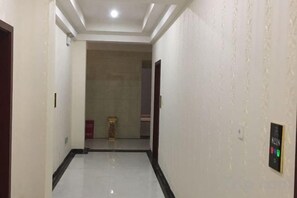A corridor with a tiled floor, a door on the left, and a wall-mounted control panel on the right. - Zhongjiang Fengshang Hotel (Zhongjiang)