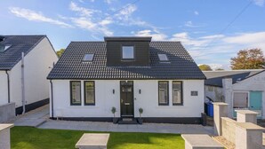 A two-story house with a dark roof, white walls, and a small front garden.