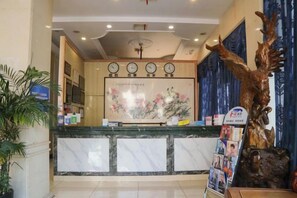 A reception area with a marble counter, a clock, a wall-mounted screen, and a decorative plant. - Daying Hotel (Ningbo)