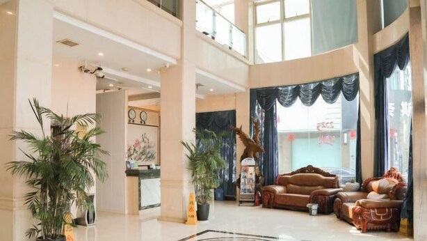 A spacious lobby with a high ceiling, a central seating area with a sofa and armchairs, and potted plants. - Daying Hotel (Ningbo)