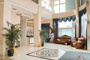 A spacious lobby with a high ceiling, a central seating area with a sofa and armchairs, and potted plants. - Daying Hotel (Ningbo)