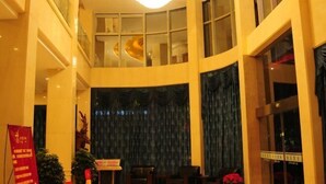 A hotel lobby with a curved ceiling, large windows, and a stage with curtains. - Daying Hotel (Ningbo)