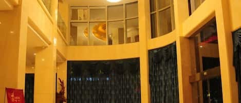 A hotel lobby with a curved ceiling, large windows, and a stage with curtains.