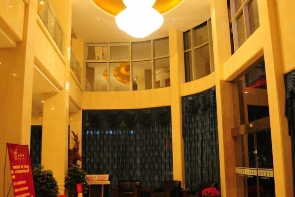 A hotel lobby with a curved ceiling, large windows, and a stage with curtains. - Daying Hotel (Ningbo)