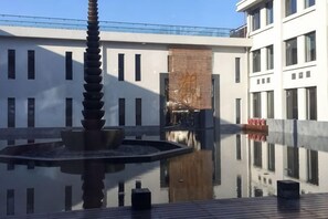 A courtyard with a water feature and a building facade. - Ruyi Resort · International Cultural Center of Buddhism, Putuoshan (Zhoushan)