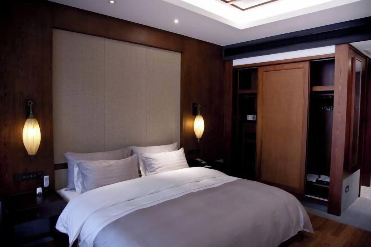 A bedroom with a large bed, wooden headboard, two wall sconces, a closet with a sliding door, and a skylight above the bed.