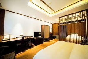 A modern hotel room with a wooden desk, a bed, and a TV. - Ruyi Resort · International Cultural Center of Buddhism, Putuoshan (Zhoushan)