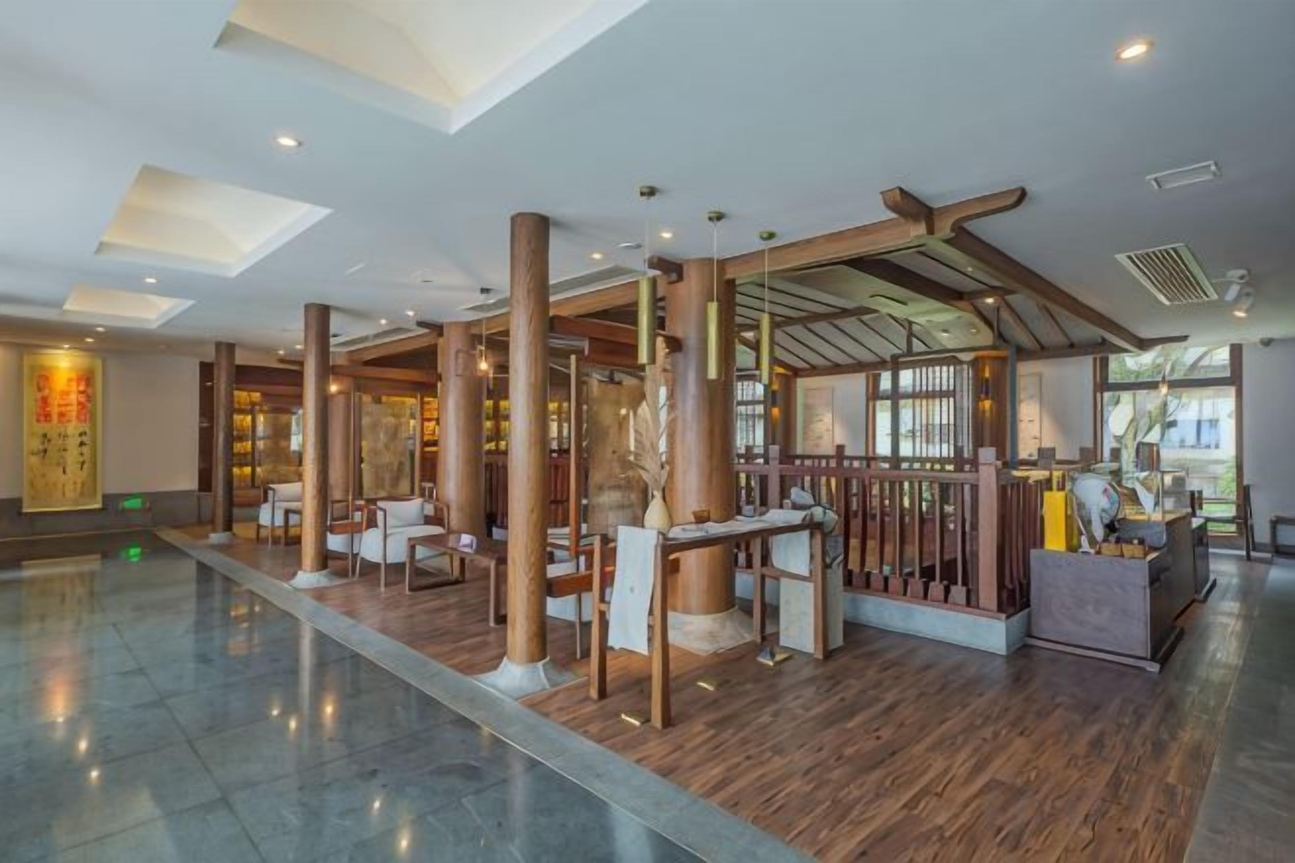 A spacious lobby with high ceilings, wooden columns, and a reception desk.