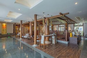 Un hall d’entrée spacieux avec de hauts plafonds, des colonnes en bois et un comptoir d’accueil.