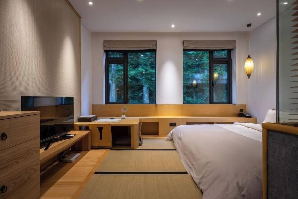 A modern hotel room with a bed, desk, and TV.