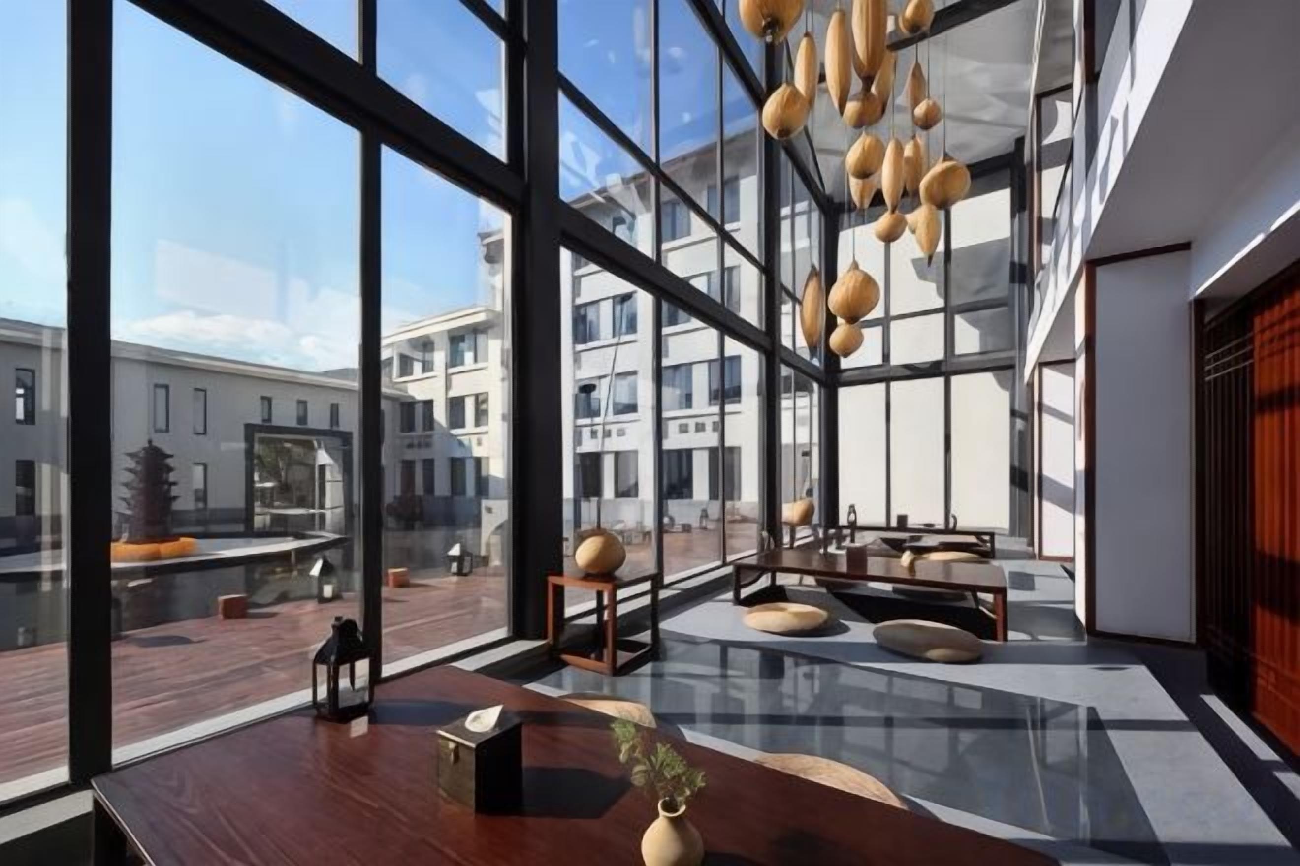 Un intérieur moderne avec de grandes fenêtres, une table en bois et des luminaires sphériques suspendus.