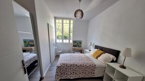 Une chambre à coucher avec un lit, des tables de chevet, une fenêtre et un luminaire suspendu.