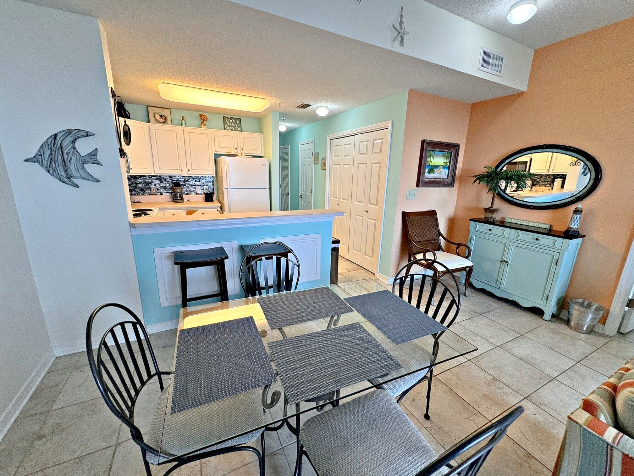 Una cocina compacta con zona de comedor, que incluye una isla central, dos taburetes de bar y una mesa con cuatro sillas.