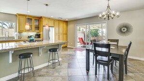 A spacious kitchen with granite countertops, wooden cabinets, and a large island with bar stools.