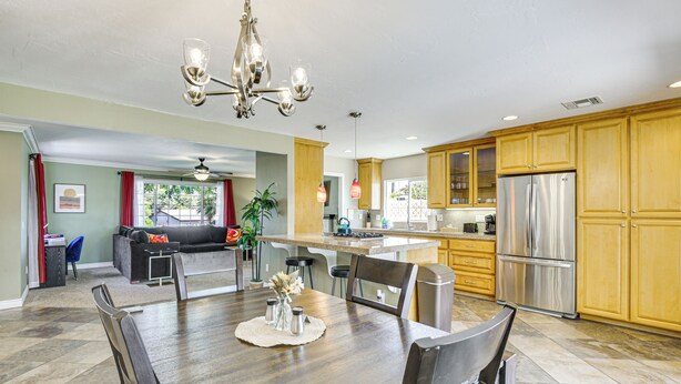 A spacious kitchen with wooden cabinets, stainless steel appliances, and a dining area with a wooden table and chairs.