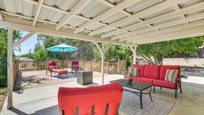 A covered patio area with outdoor furniture, including a red sofa and chairs, and a table.