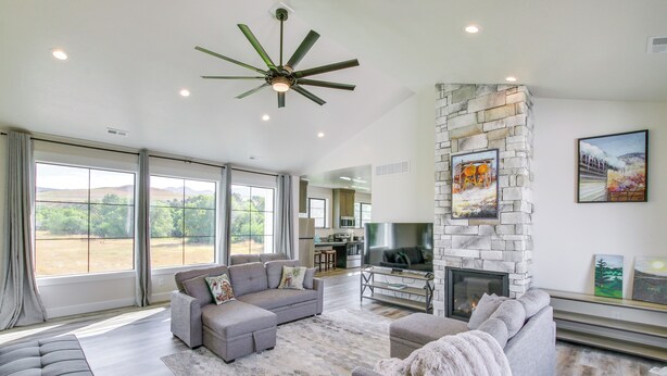 Tilava olohuone, jossa on harmaa sohva, takka ja kivestä tehty korosteseinä.