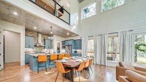 Une cuisine spacieuse dotée d’un îlot central, de planchers en bois et d’un coin repas avec des chaises orange.