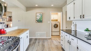 Une cuisine avec des meubles blancs, une cuisinière, un four à micro-ondes et un lave-linge.