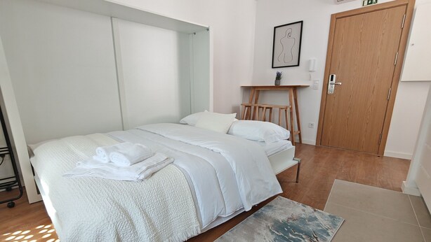 Une chambre à coucher moderne avec un lit, une table de chevet et une porte en bois.
