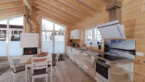Une cuisine moderne avec des poutres en bois, une cheminée et une grande fenêtre.