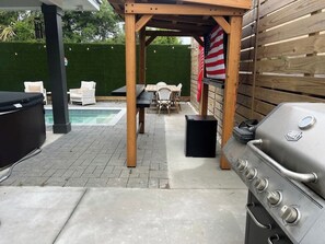 Un patio al aire libre con una parrilla, asientos y una piscina.