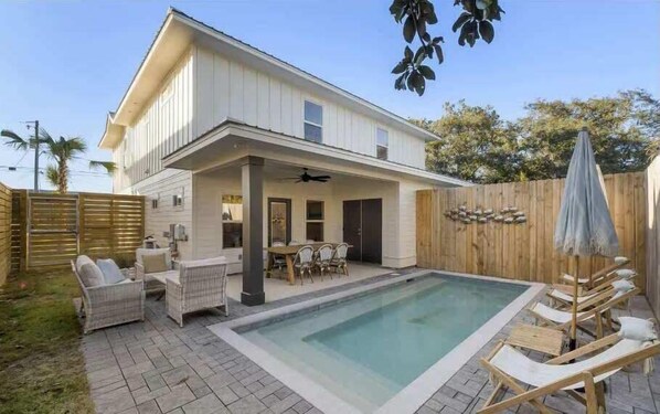 Une maison à deux étages dotée d’un patio couvert et d’une piscine.