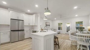 A modern kitchen with white cabinetry, a stainless steel refrigerator, and a central island.