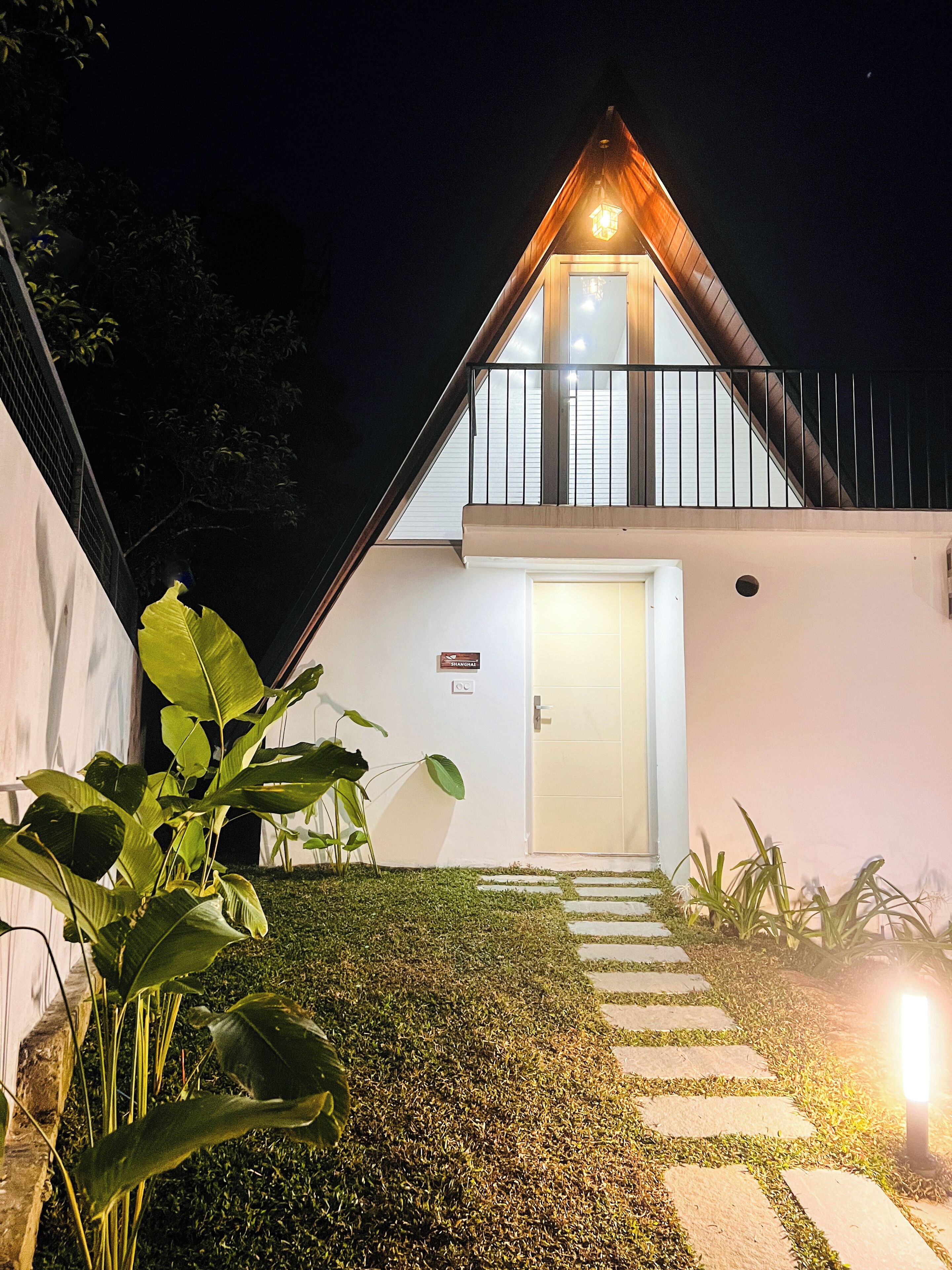 Un bâtiment moderne doté d’un toit en pente, d’un balcon avec une balustrade et d’une porte sur laquelle est apposée une enseigne indiquant un centre de bien-être.
