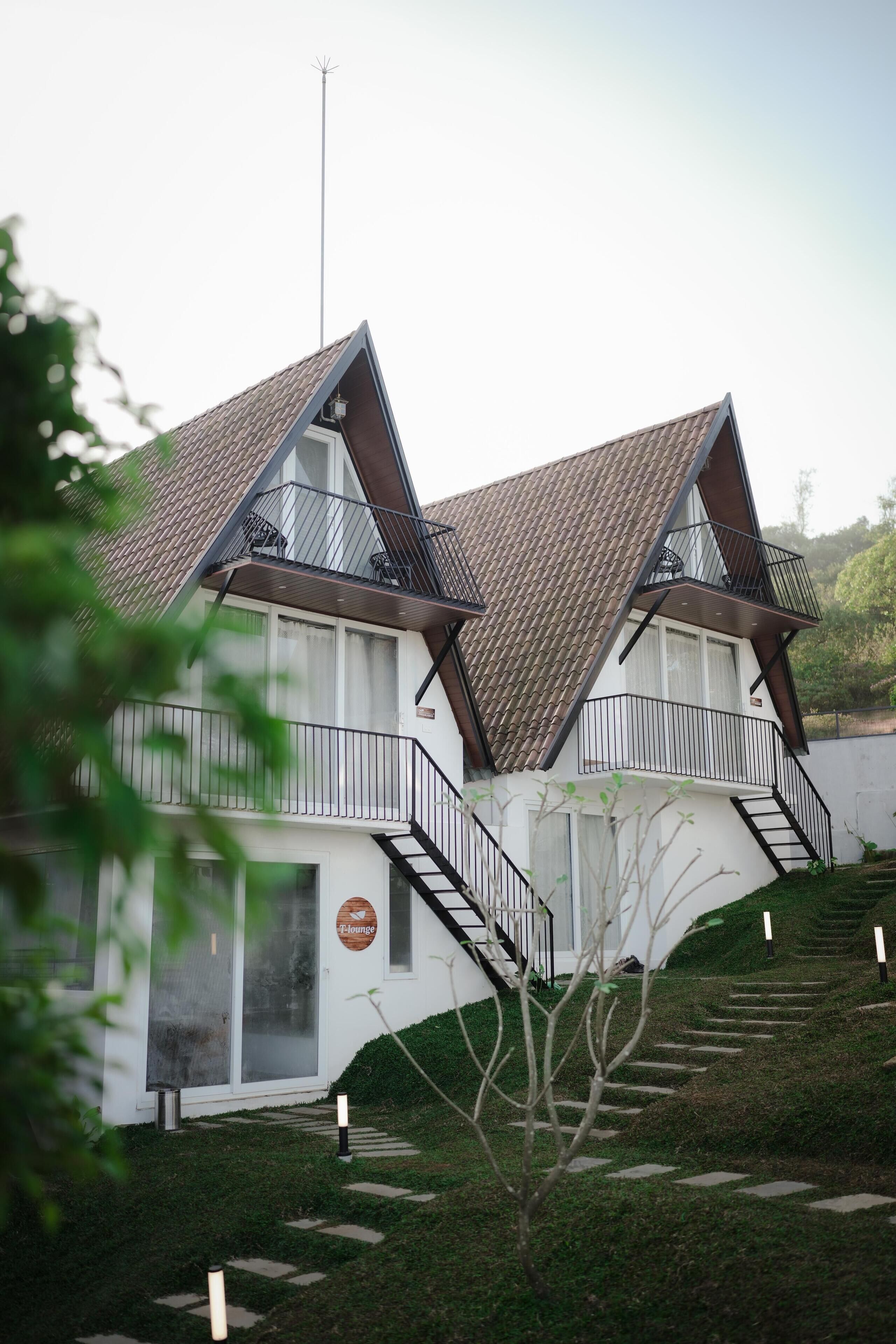 Un edificio moderno con techo inclinado, dos balcones y una escalera que lleva a la entrada.
