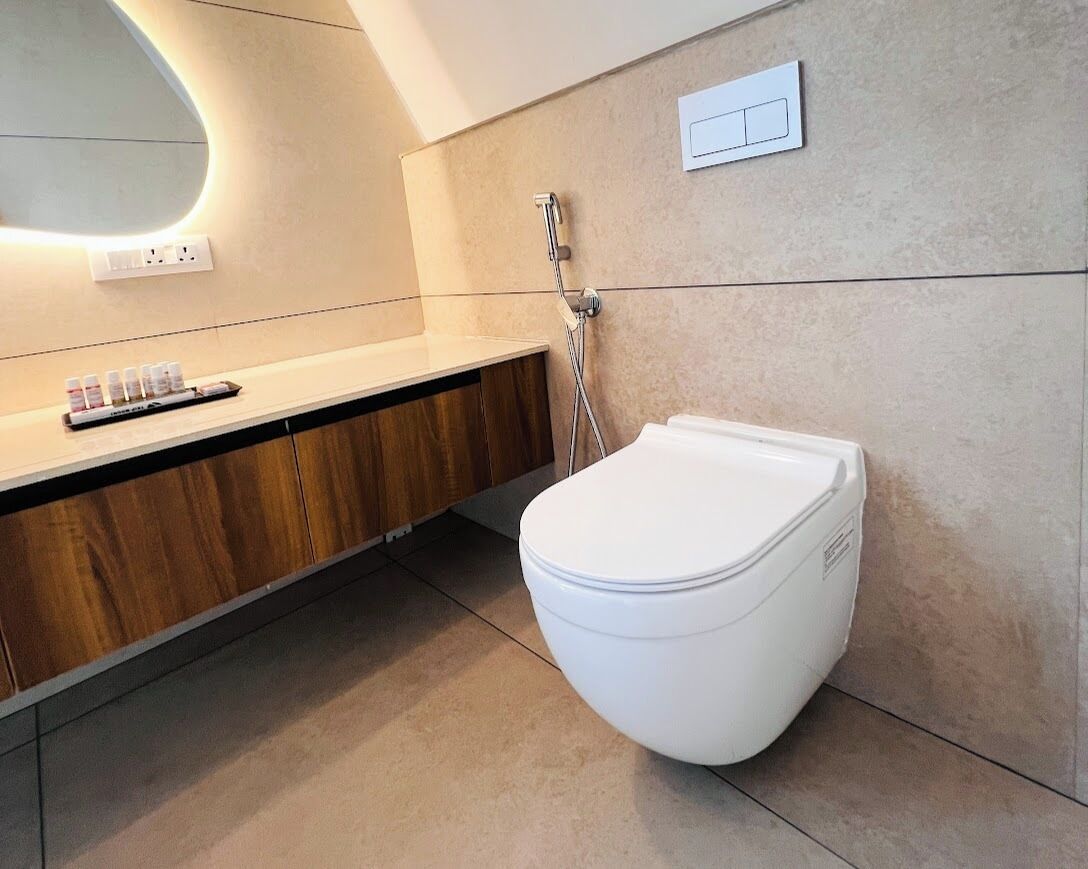 A modern bathroom with a white toilet, a wooden vanity, and a shower.