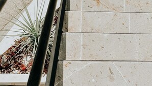 Una escalera con baldosas color beige y una barandilla de metal.