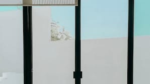 Una habitación con una mesa de centro de vidrio, un sofá y vistas a un balcón a través de grandes puertas corredizas de cristal.