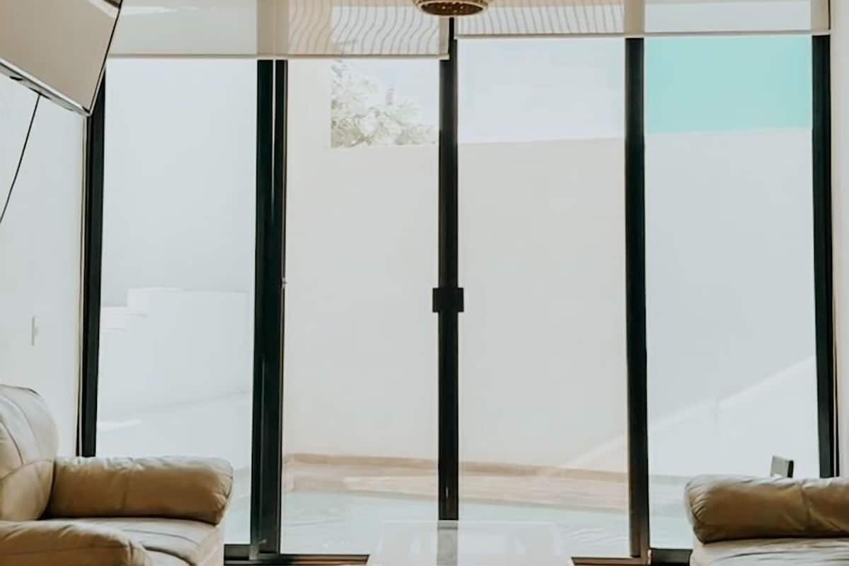 Uma sala de estar moderna com teto alto, janelas amplas e luminária trançada central.