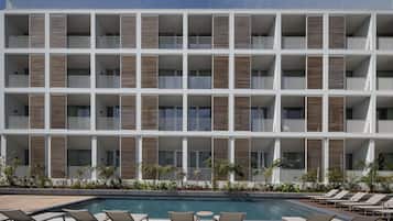 Um hotel moderno com várias varandas, piscina e espreguiçadeiras.