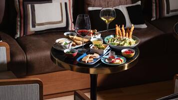 Una mesa de comedor con diversos platos y bebidas, sobre un sofá de cuero con cojines estampados.