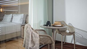 Ein modernes Hotelzimmer mit einem Bett, einem kleinen Tisch mit Fernglas und einem Korbstuhl.