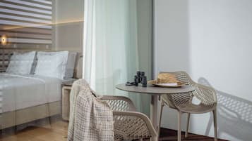 Quarto de hotel moderno com uma cama, uma mesinha com binóculos e uma cadeira de vime.