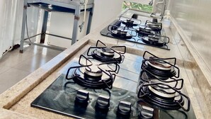 A kitchen with a gas stove, a pressure cooker, and a stainless steel range hood. - Hostel Gravatá (Piracicaba)