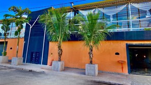 A modern building with a glass facade, palm trees, and a clear sky. - Hostel Gravatá (Piracicaba)
