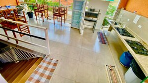 A spacious kitchen with a dining area, a staircase, and a view of the neighborhood. - Hostel Gravatá (Piracicaba)