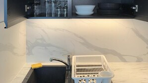 Una cocina moderna con un fregadero integrado, un escurreplatos y estantes con cristalería y platos.
