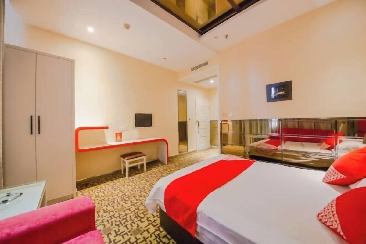 Ein Hotelzimmer mit Bett, Schreibtisch, Stuhl, Kleiderschrank und Spiegel.