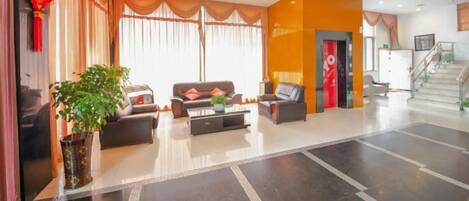 A hotel lobby with a reception desk, seating area, and a staircase.