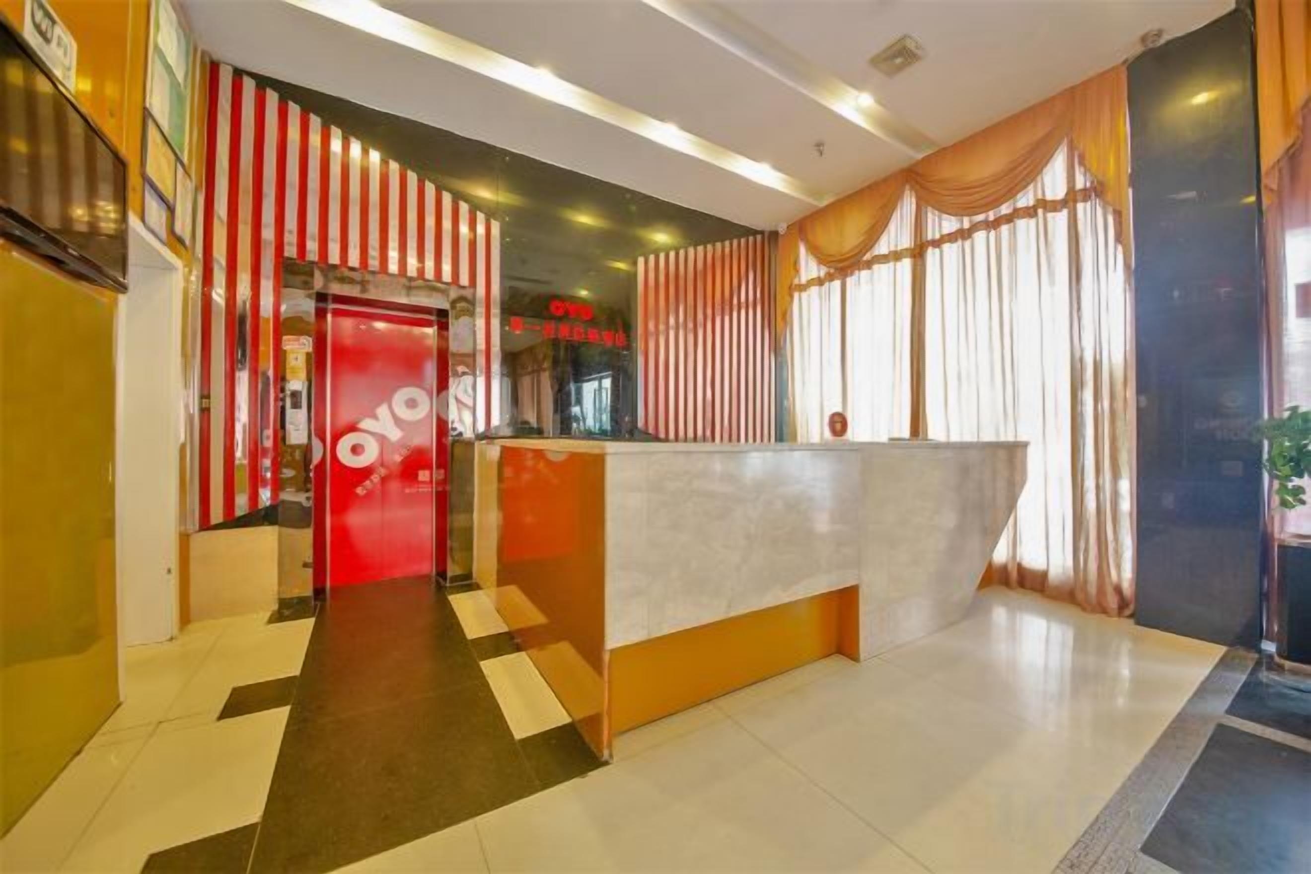 Zona de recepción de un hotel con un mostrador, una puerta roja y un área de registro.