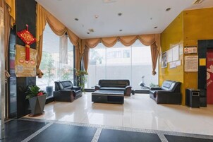Un hall de hotel con mostrador de recepción, zona de estar y grandes ventanales.