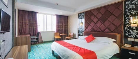 A hotel room with a large bed, a desk, a chair, a TV, and a window with curtains.