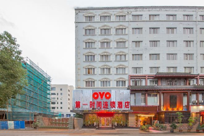 A hotel with a prominent red sign, a traditional architectural style, and a modern building in the background.